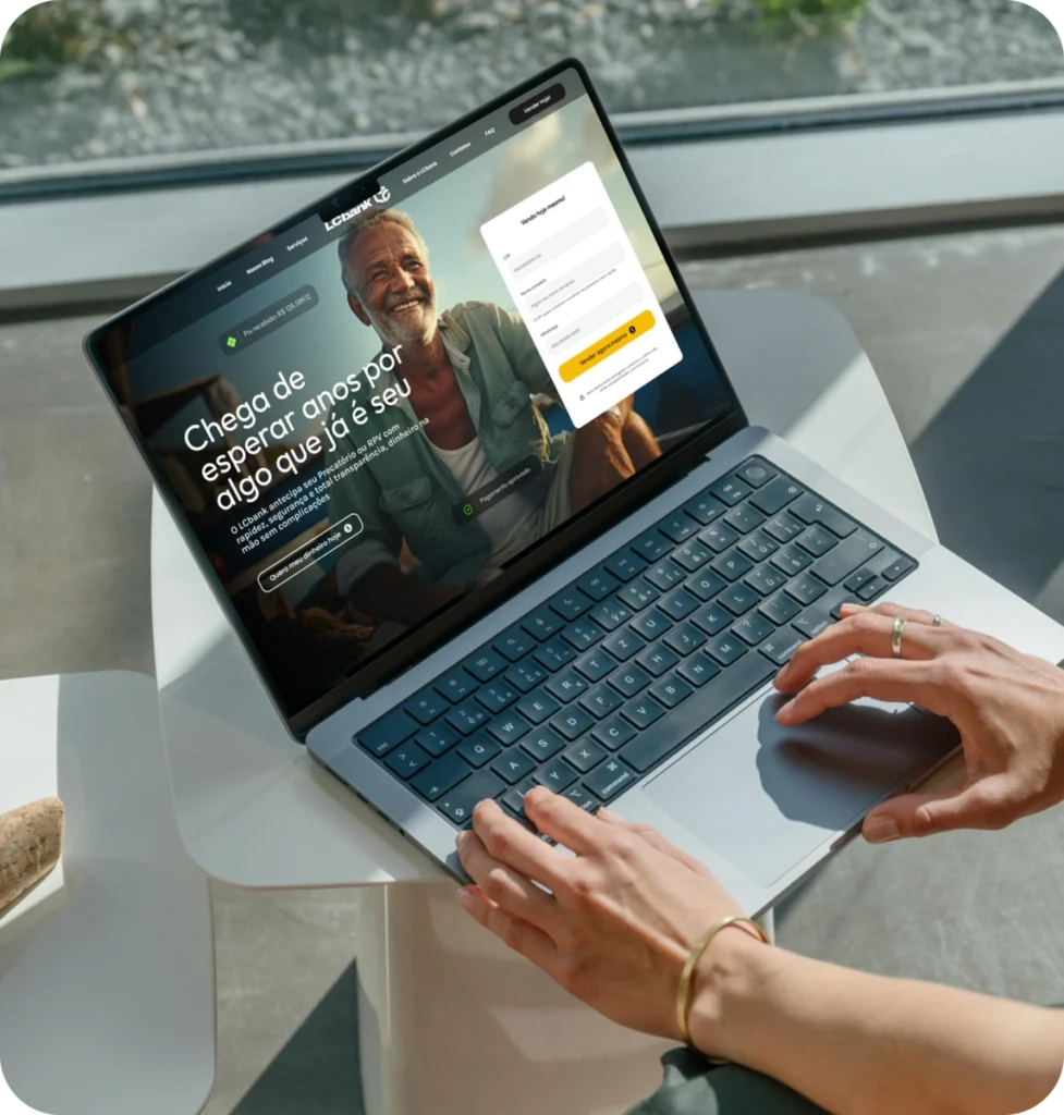 Laptop aberto exibindo site do LCbank com homem sorridente e interface de login.