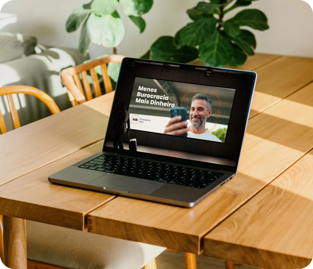 Laptop com tela mostrando vídeo "Menos Burocracia Mais Dinheiro" do LCbank